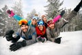 Smiling friends on winter holidays - Skiers lying on snow and ha